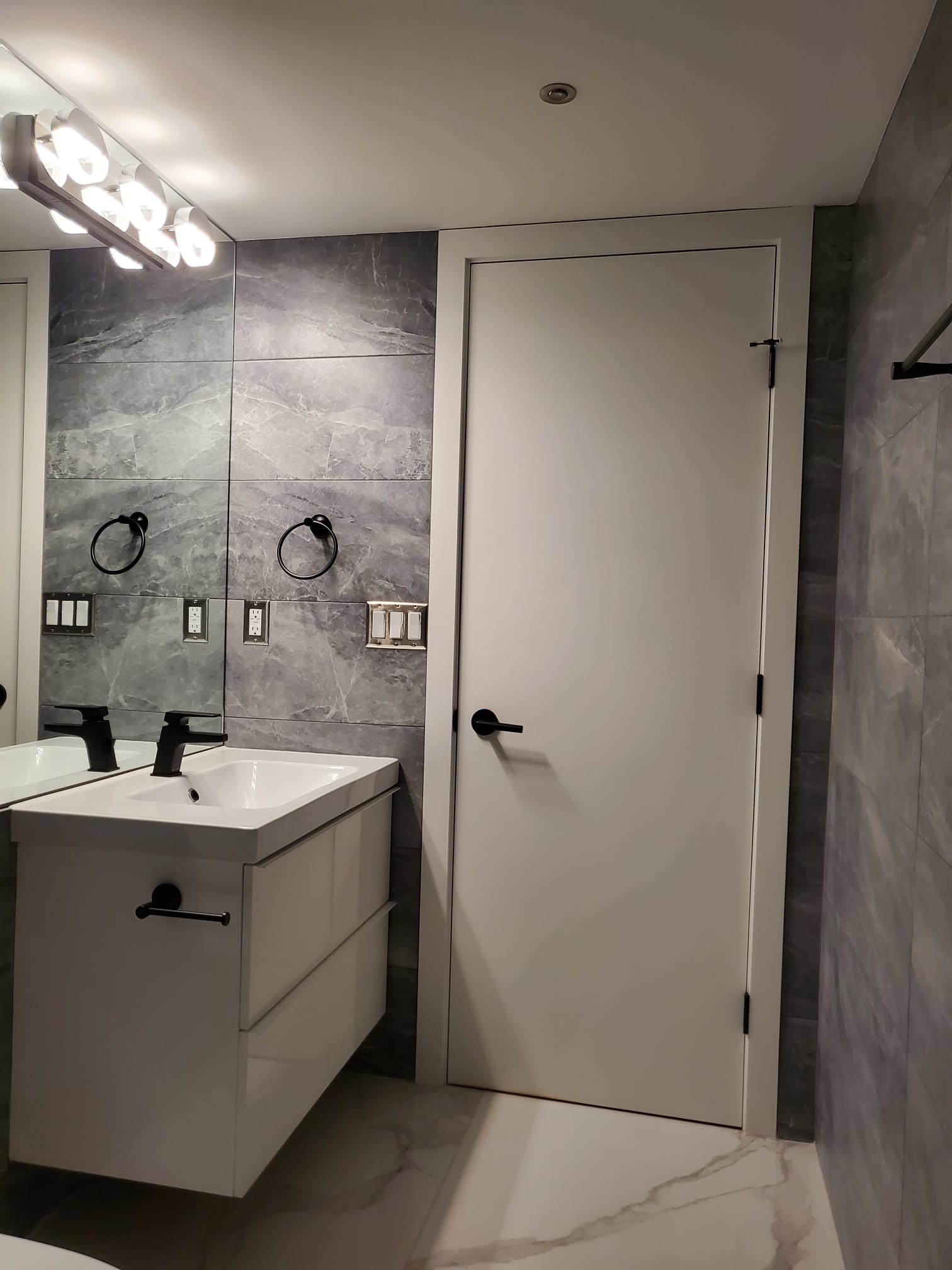 Floating vanity with black fixtures and stone tile