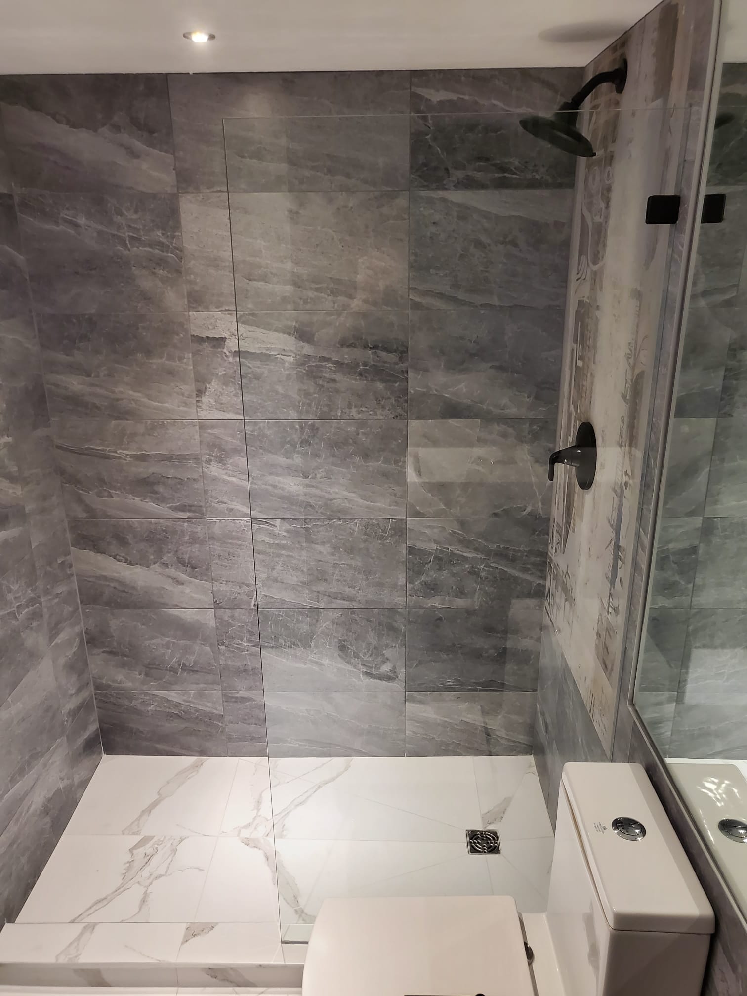 Walk-in shower with grey marble-look tile and black fixtures