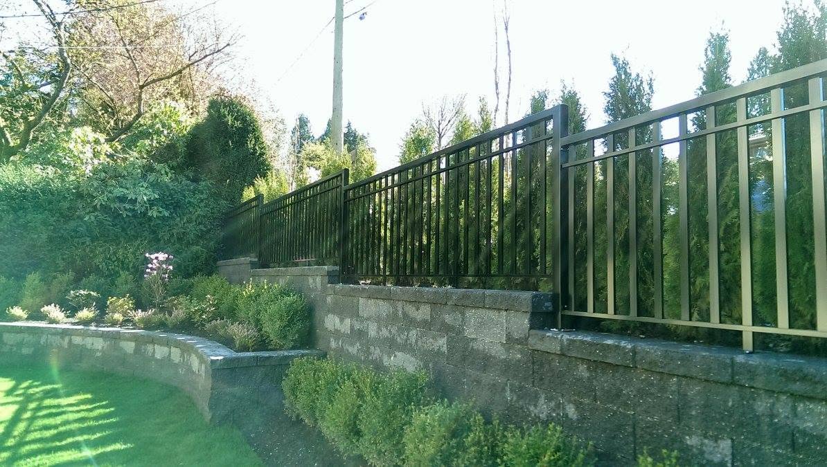 Black aluminum picket fence on a stone retaining wall