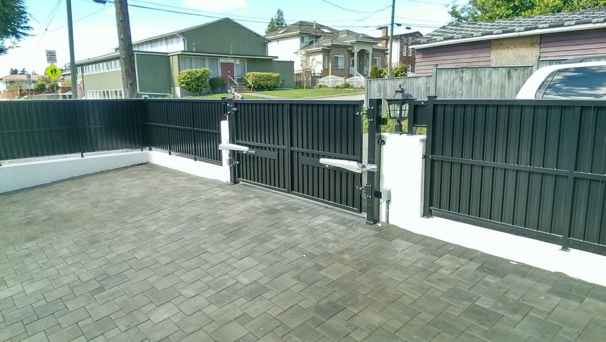 Paving stone courtyard with black privacy fence and automated gate