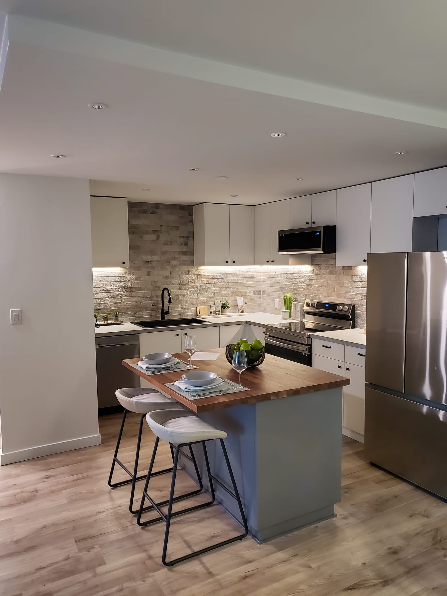 Compact kitchen with butcher-block peninsula and stone backsplash