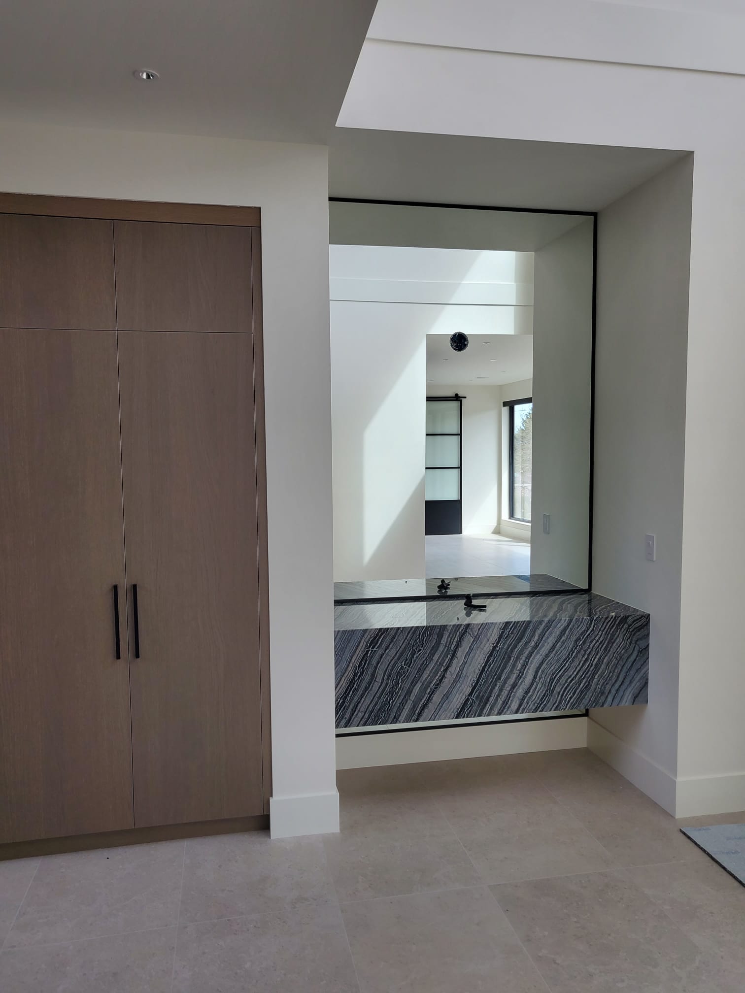 Entry with oak cabinetry, full-height mirror and stone bench
