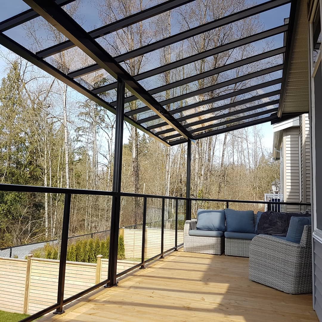 Glass roof patio cover on black aluminum frame over a cedar deck