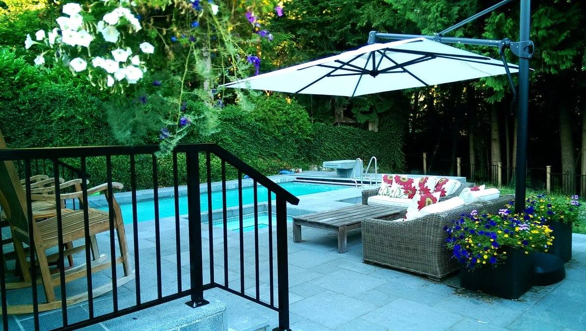 Pool patio in large format grey stone pavers with aluminum railing