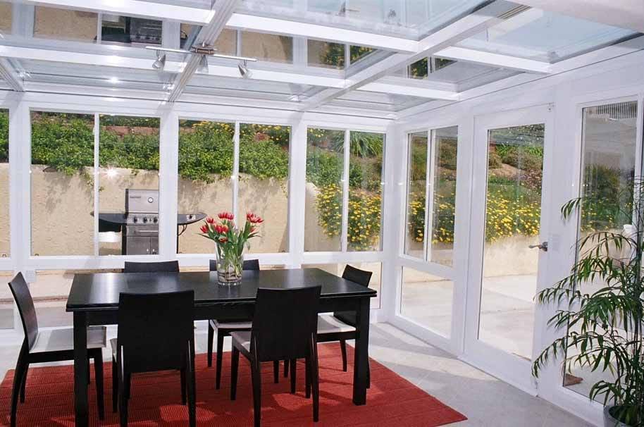 White-framed glass solarium with glass roof and dining area